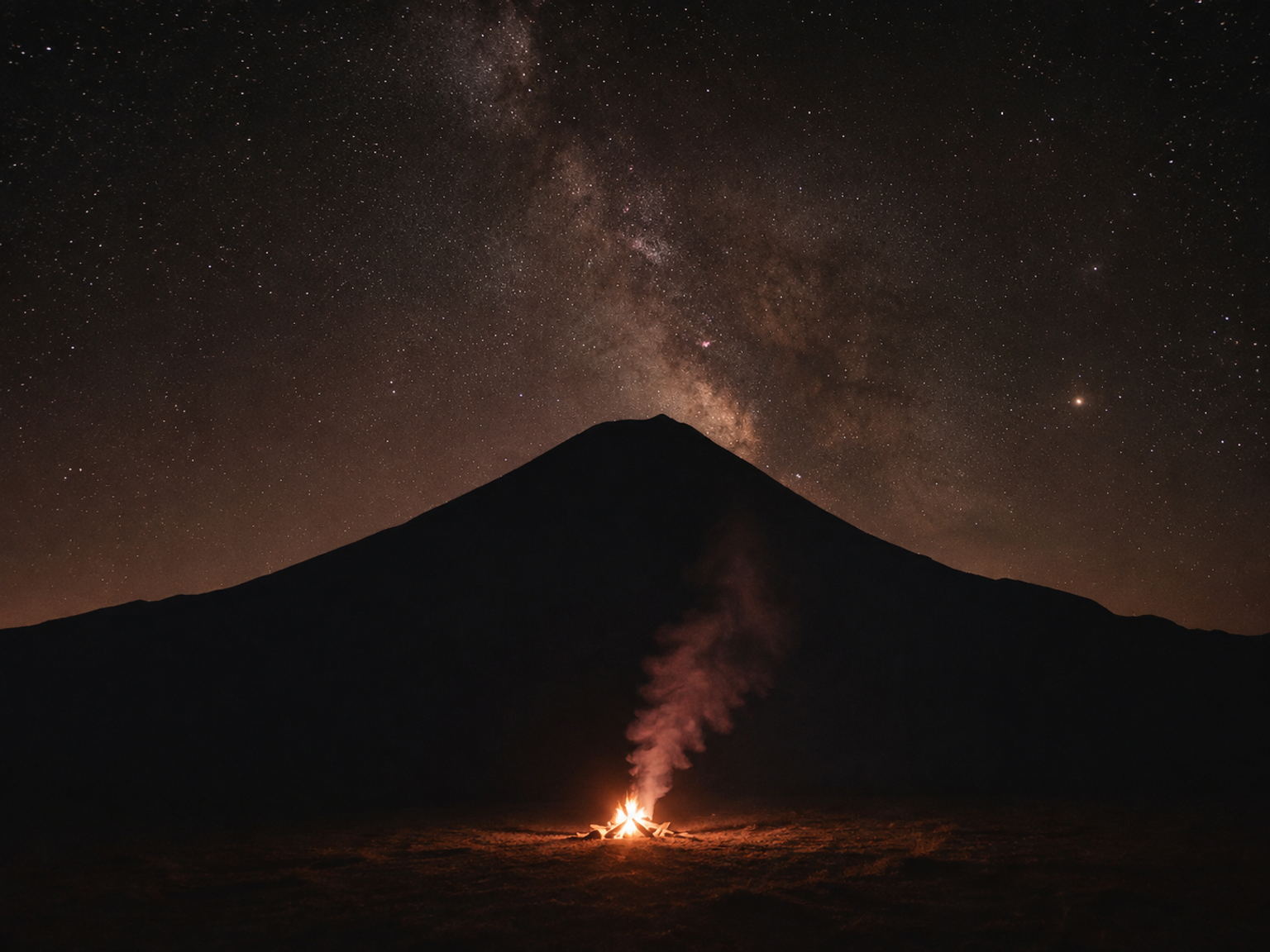 Small campfire on a mountain plateau at night.